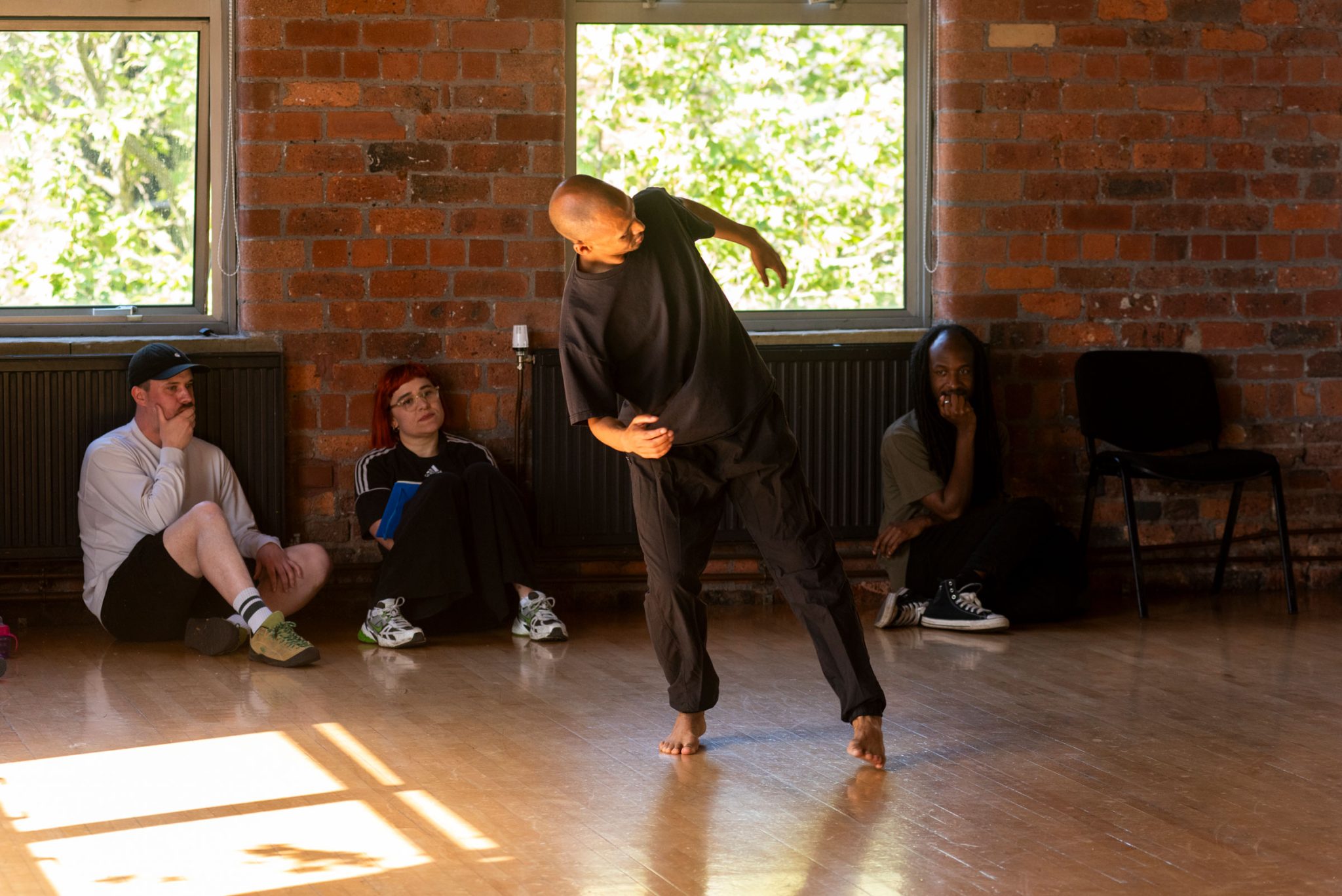 Tiran Willemse in a dance studio moves with a people sat around the edge